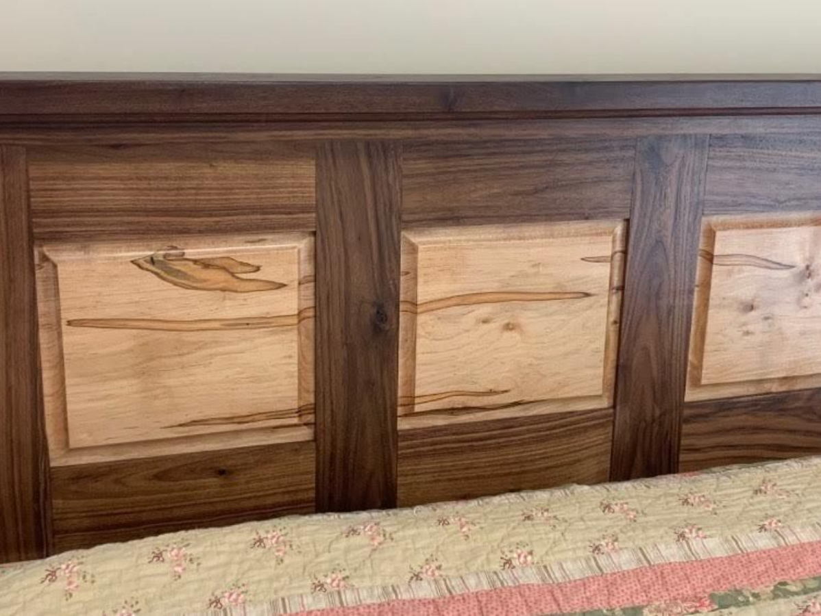 Wooden headboard with dark walnut panels framing lighter wood squares.