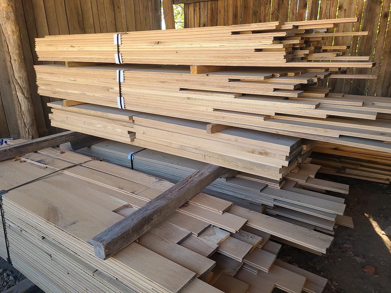 Wooden planks stacked on pallets inside a wooden structure.