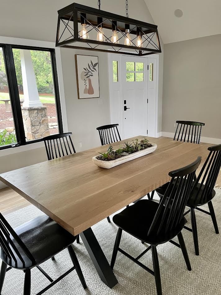 Dining room with a wooden table, black chairs, and a decorative light fixture.