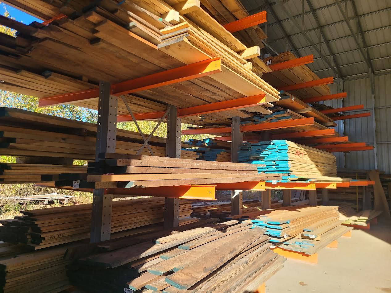 Wooden planks of various types stacked on industrial shelving inside a warehouse.