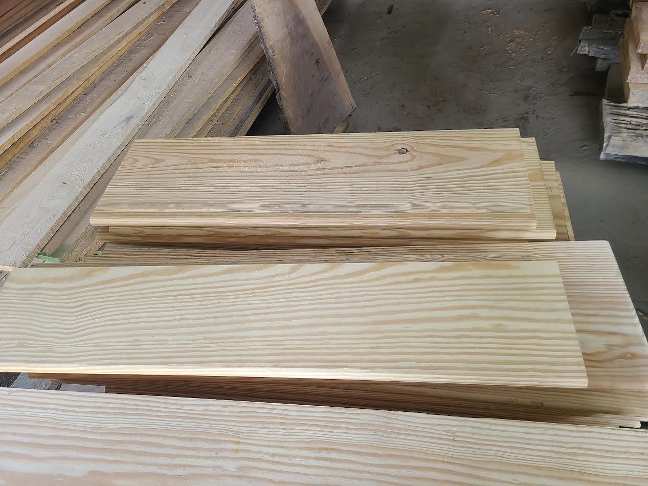 Stack of light-colored wooden planks with visible grain.