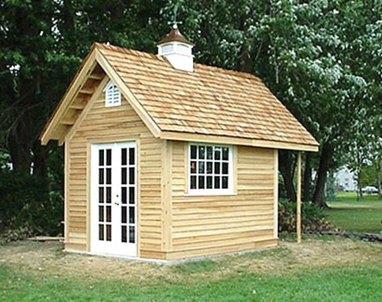 Wooden shed with shingle roof, double doors, window, and small cupola in a grassy yard.