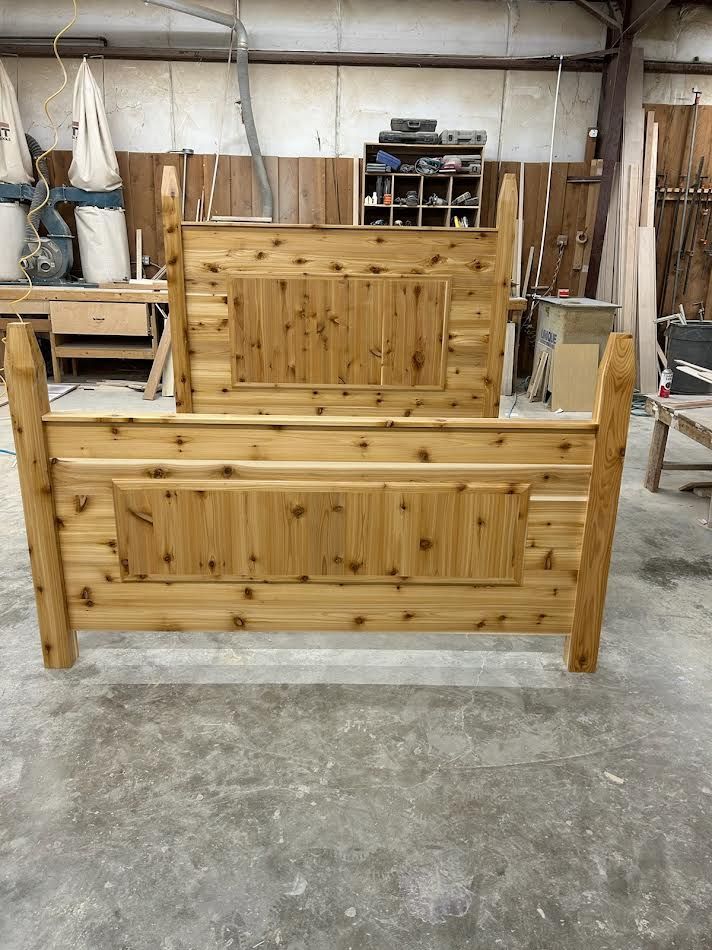 Wooden bed frame in a workshop, showcasing the headboard and footboard.