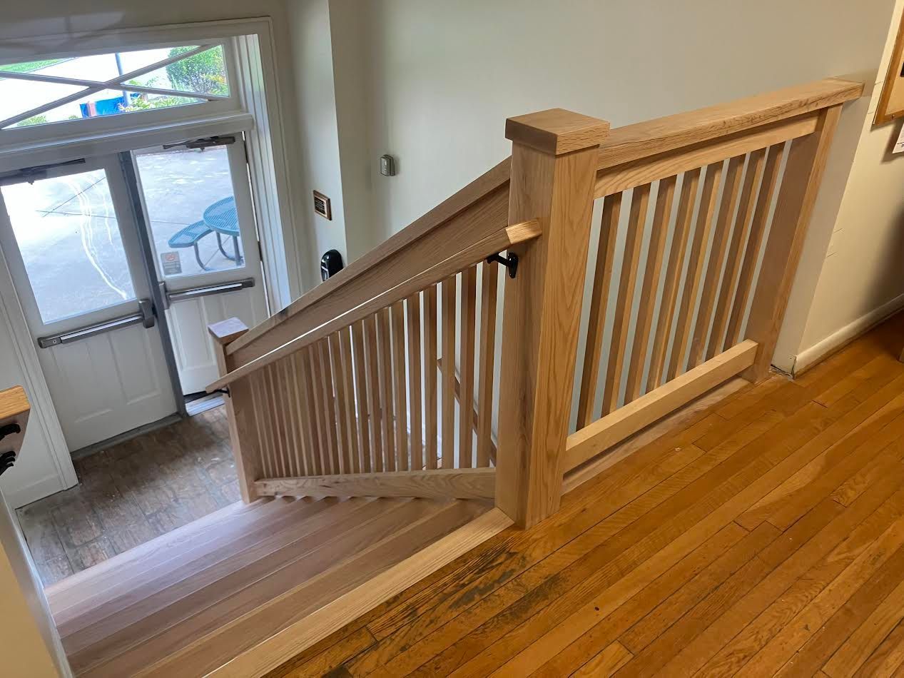 Wooden staircase with railing leading down, door in the background.