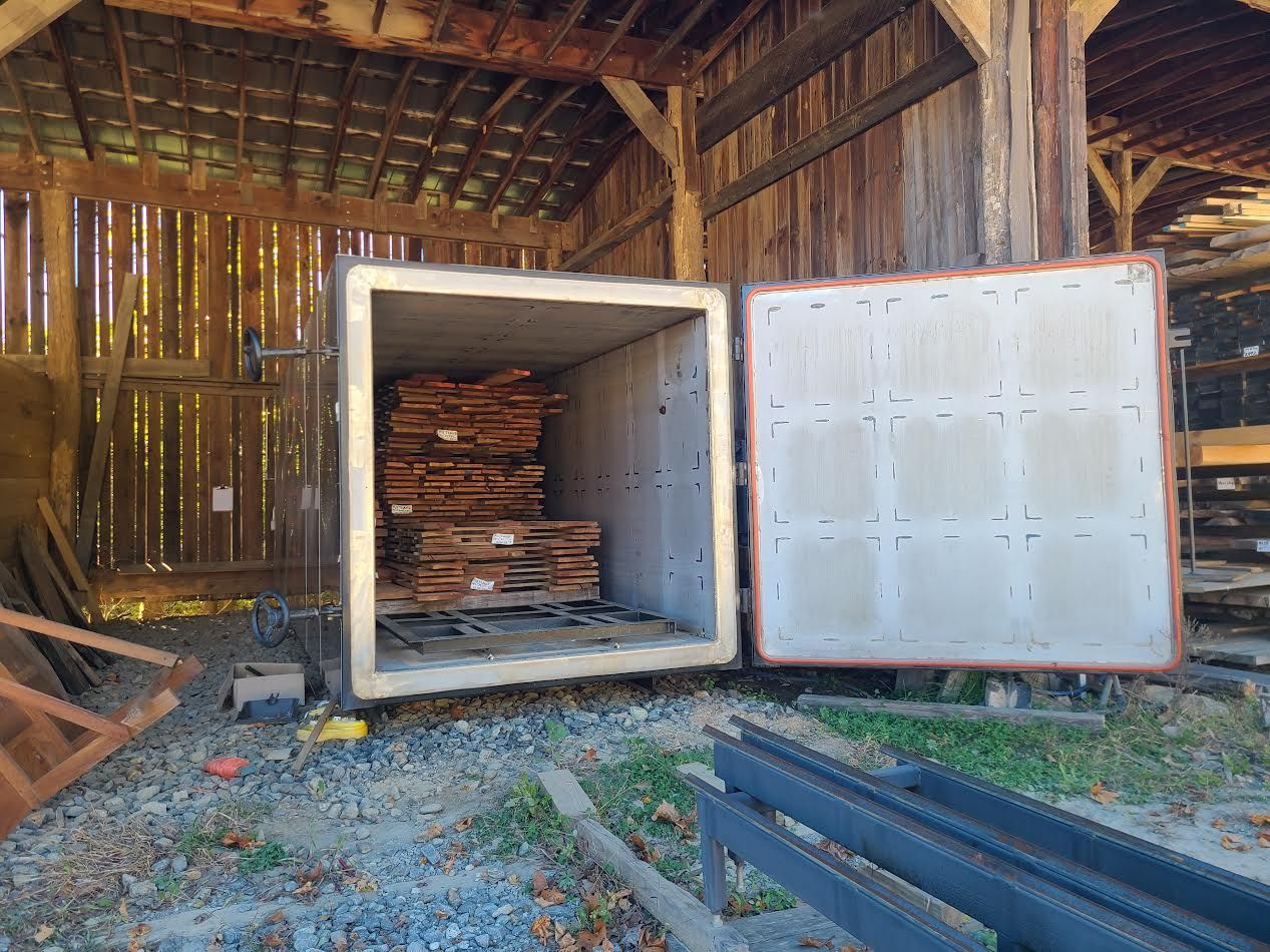 Opened kiln in a wooden barn, filled with stacked lumber.