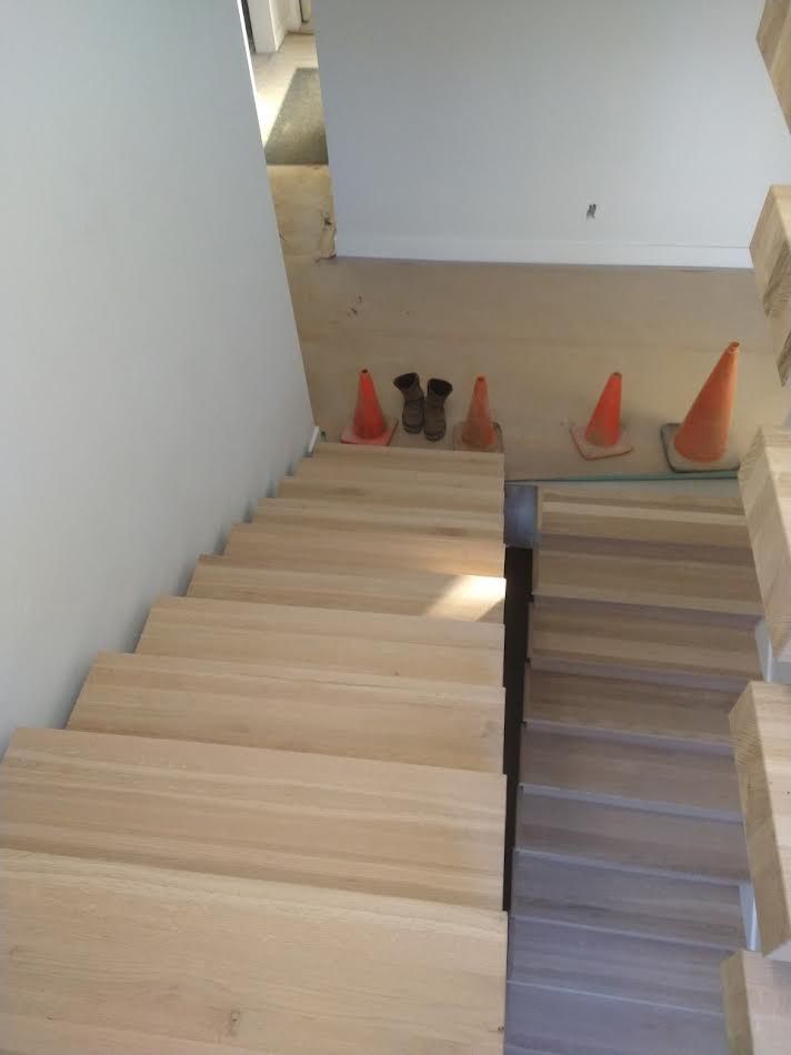 Staircase with light wood steps. Orange cones and boots are on the landing.