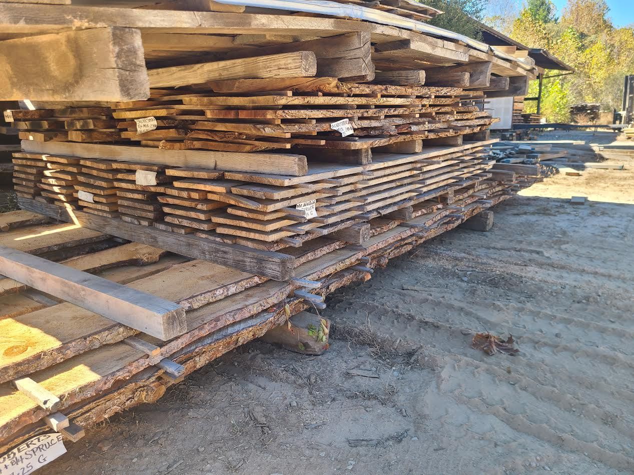 Stacked wooden planks on pallets in an outdoor setting.