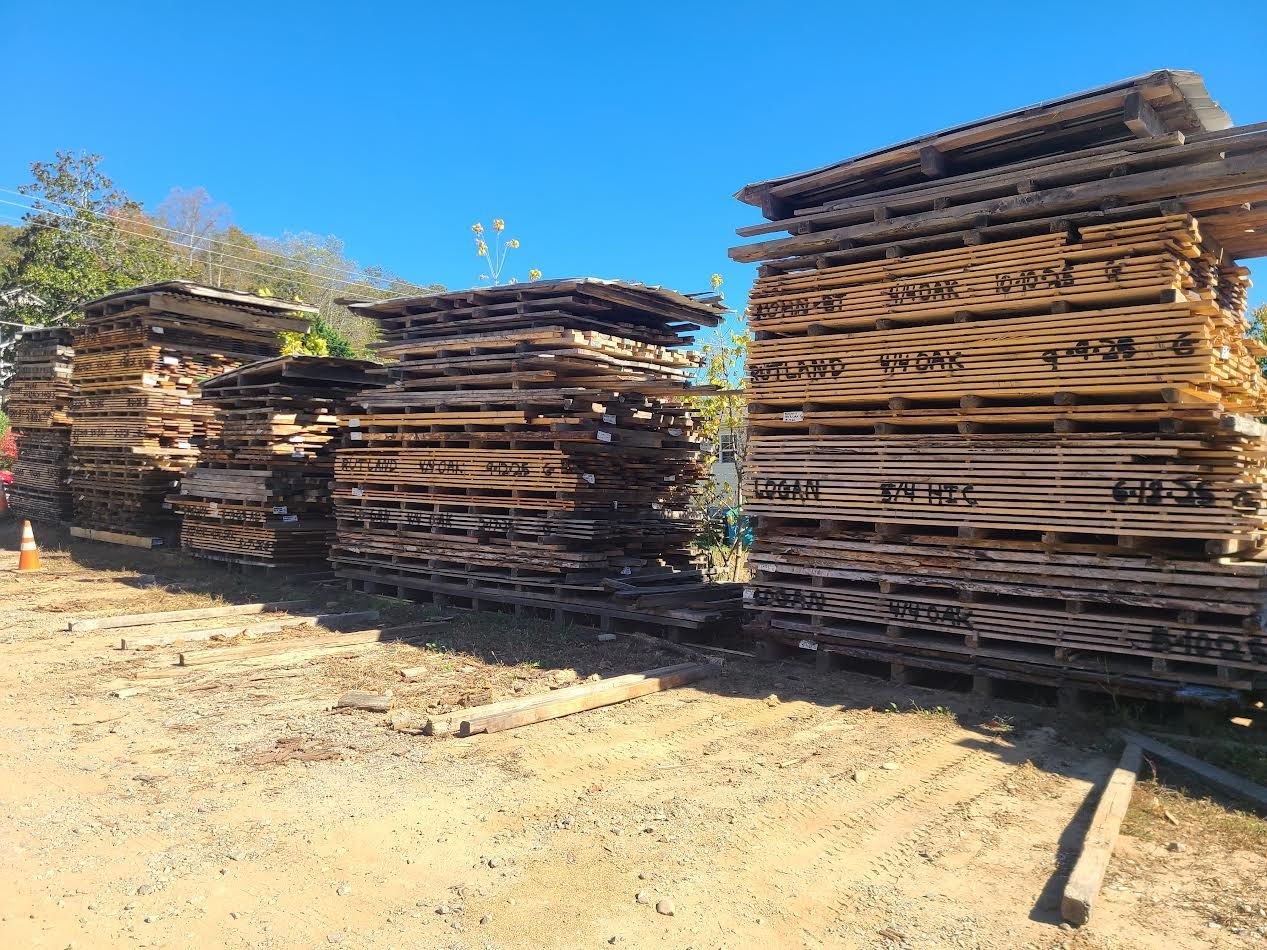 Stacks of wooden pallets outdoors under a clear blue sky.