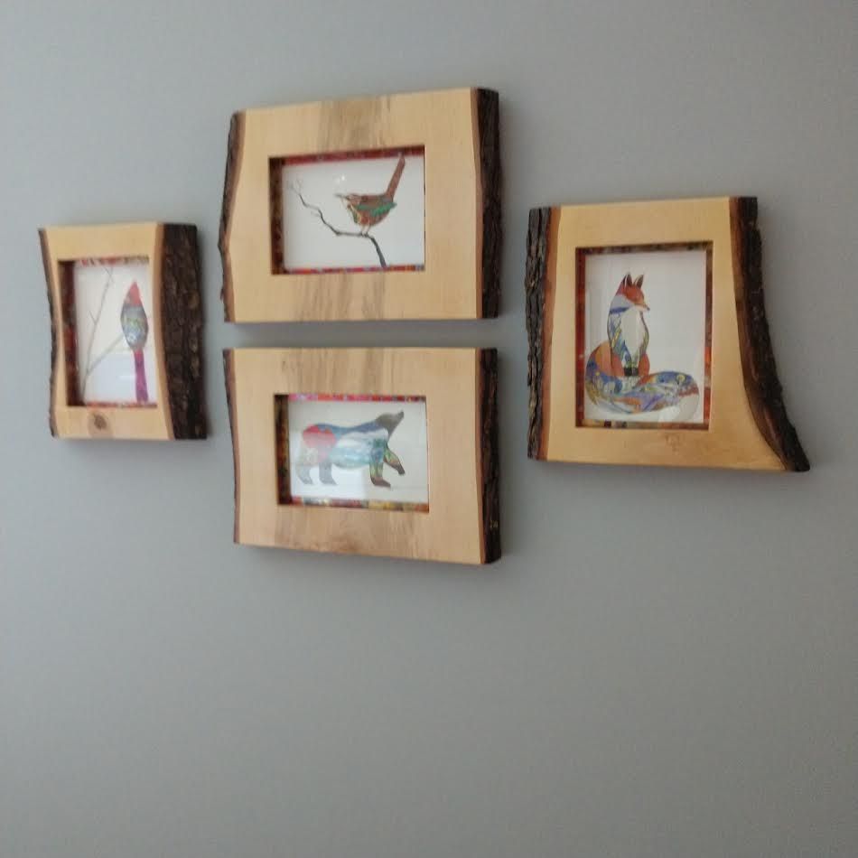 Four framed animal art prints with wood frames on a gray wall.