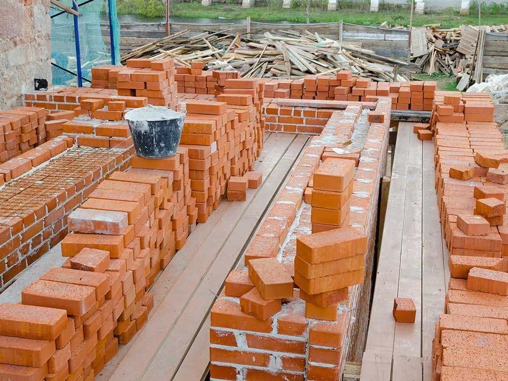 a bucket of cement sits on top of a pile of bricks