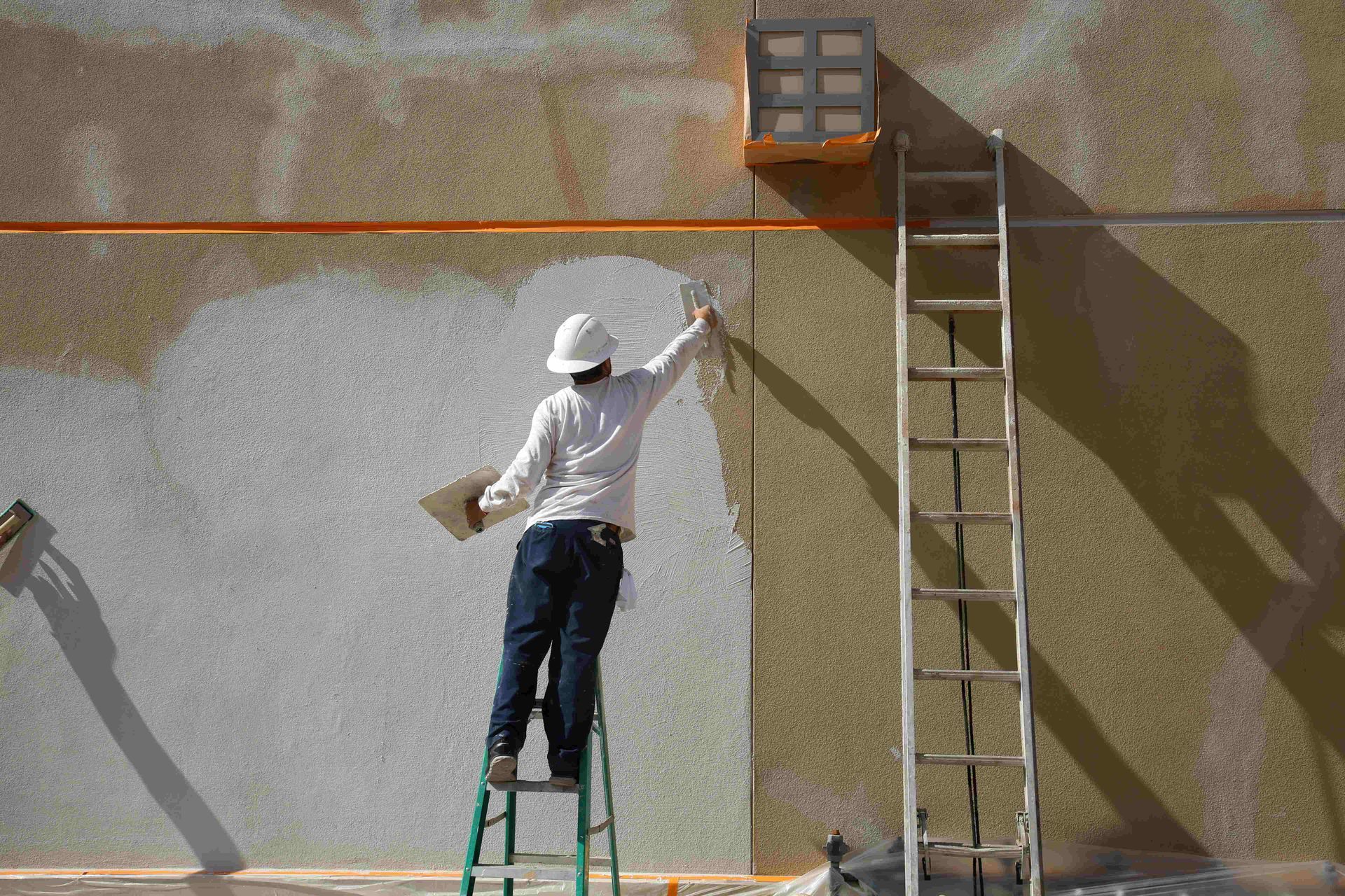 a man standing on a ladder repairing a wall