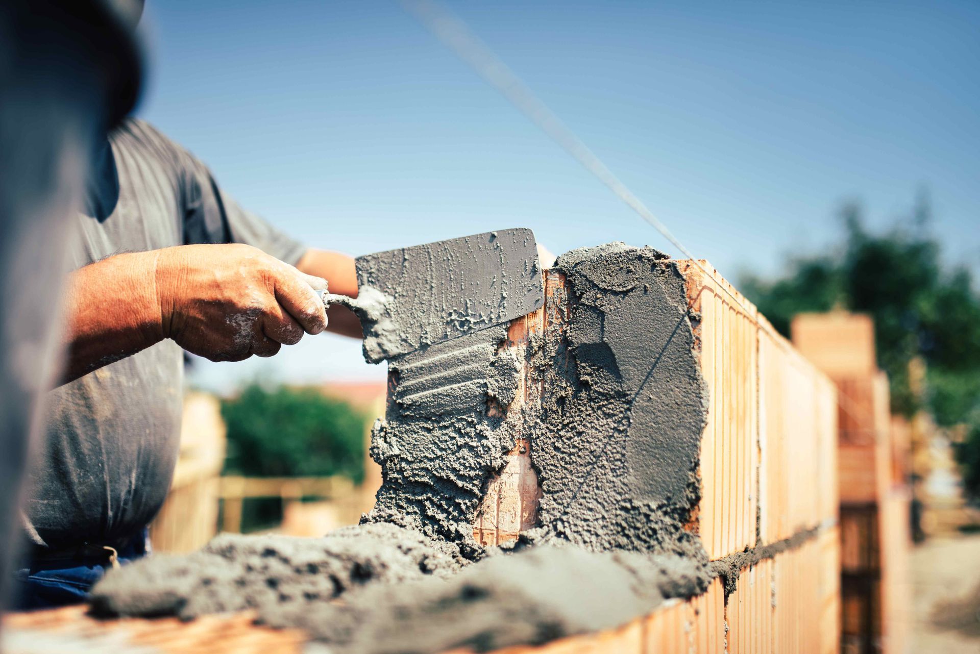 a man is using a trowel to spread cement on a brick wall