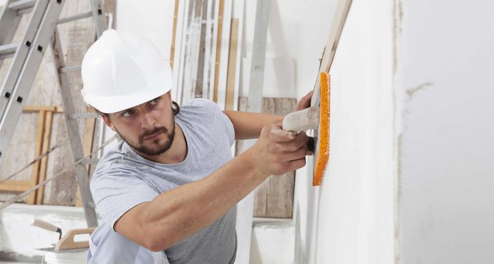 a man wearing a hard hat is painting a wall