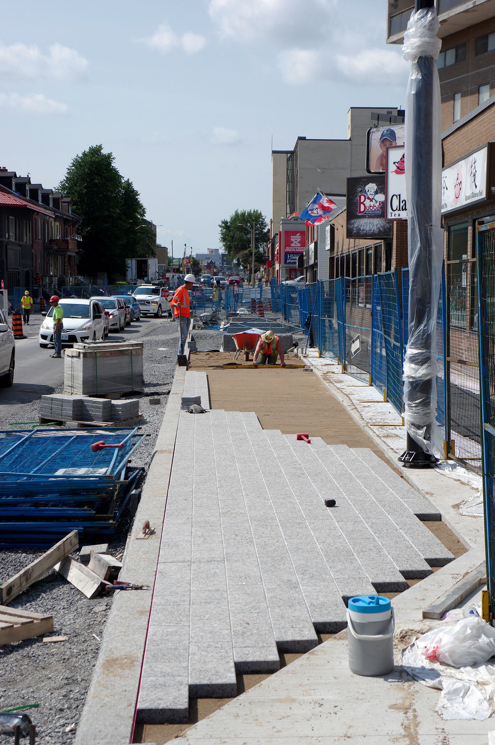 A group of construction workers are working on a sidewalk on a city street.