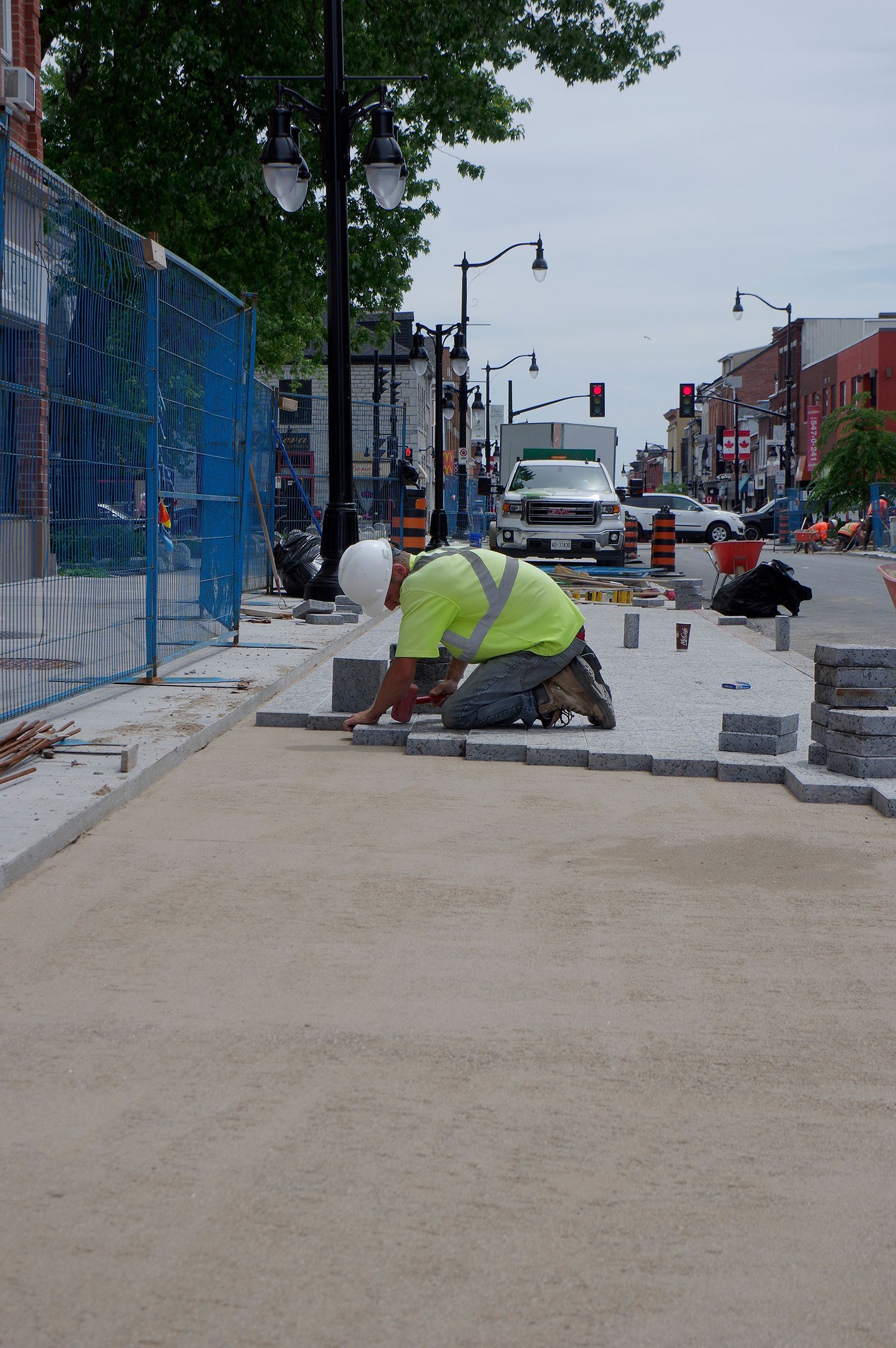 A man in a yellow shirt is kneeling down on a sidewalk.