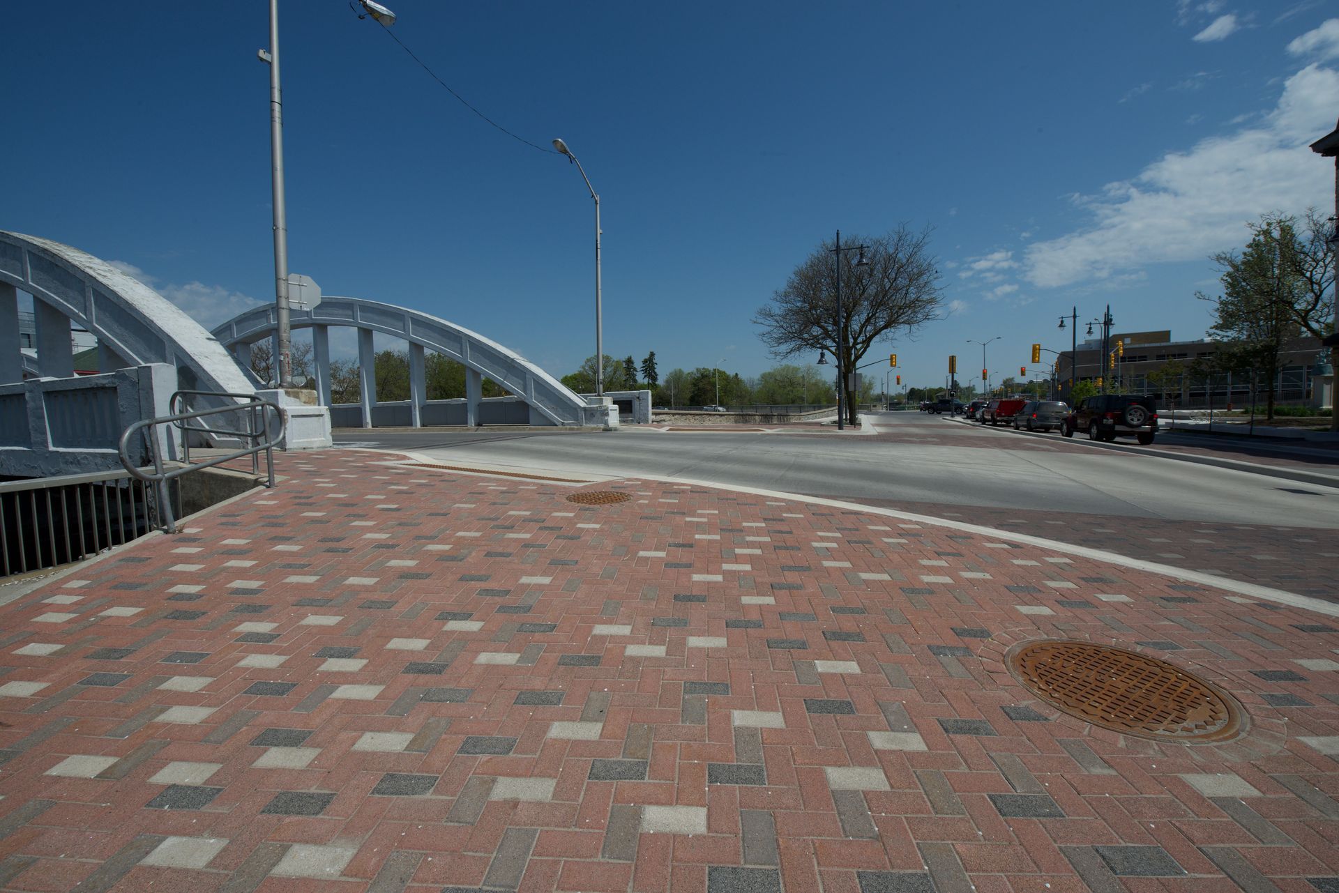 There is a bridge in the background and a brick walkway in the foreground.