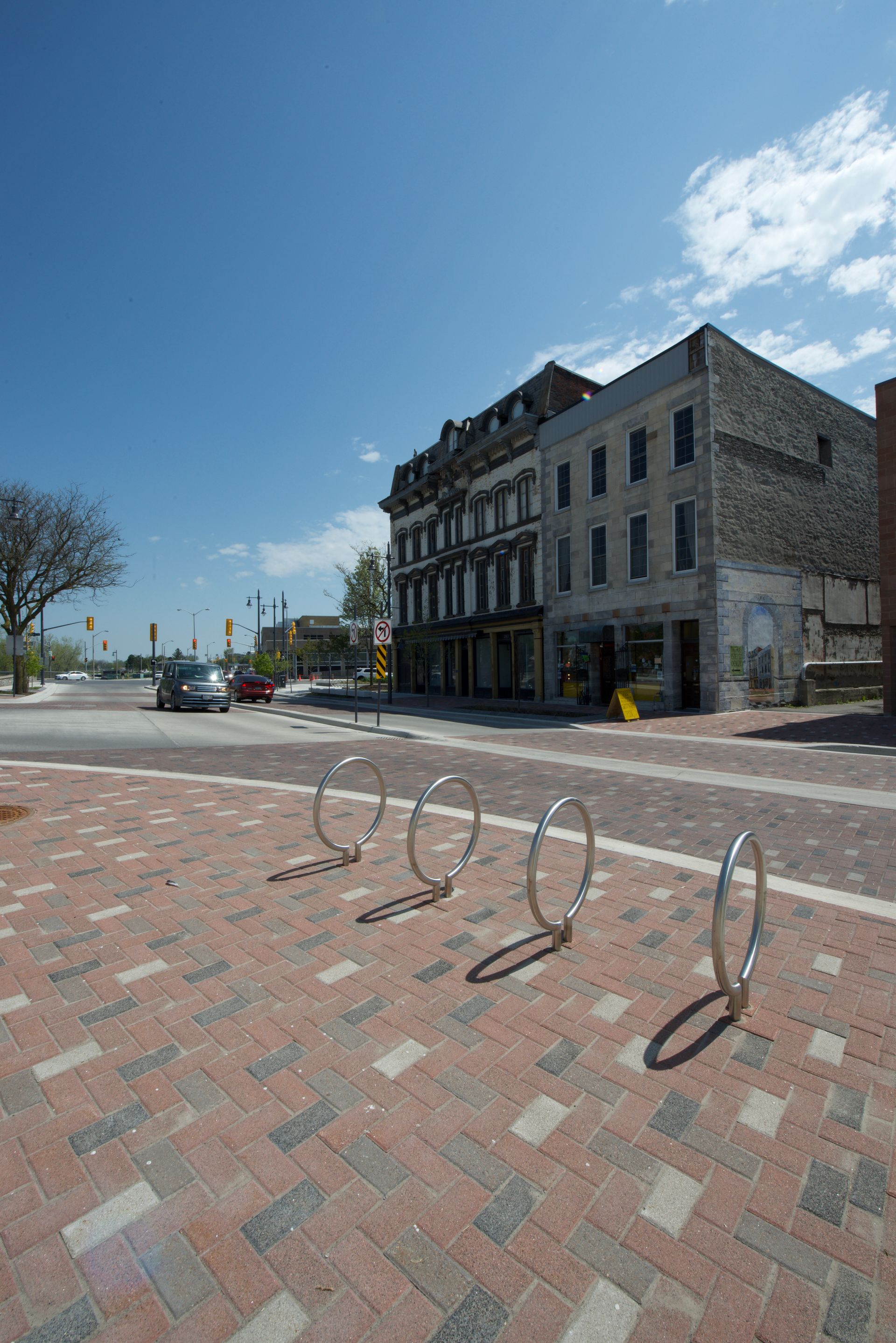A row of bike racks on a brick sidewalk in front of a building.