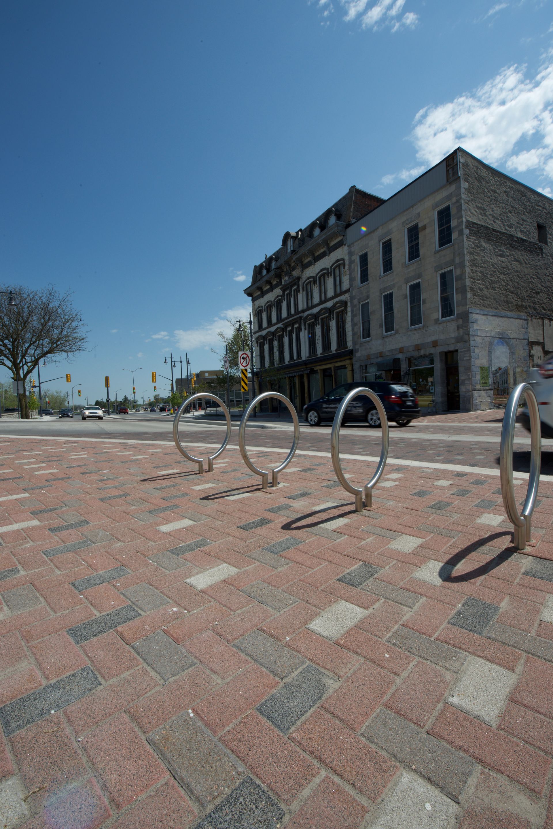 A row of bike racks on a brick sidewalk in front of a building.