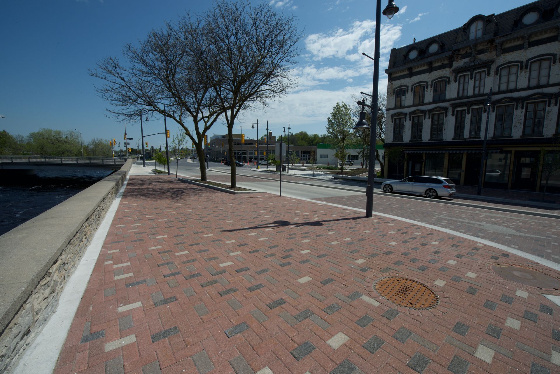 A brick sidewalk along a river with a building in the background.