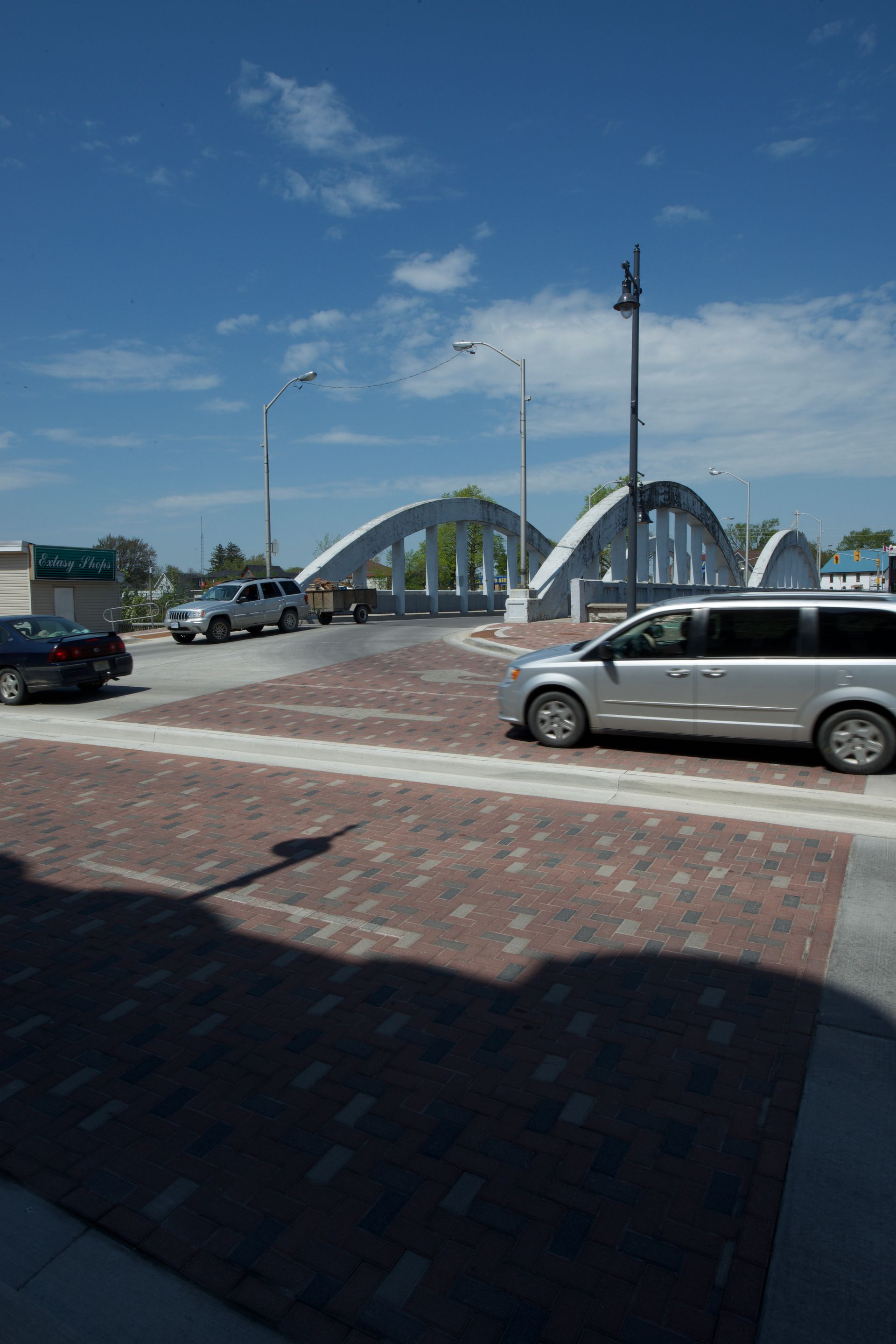 A van is parked on the side of the road in front of a bridge.