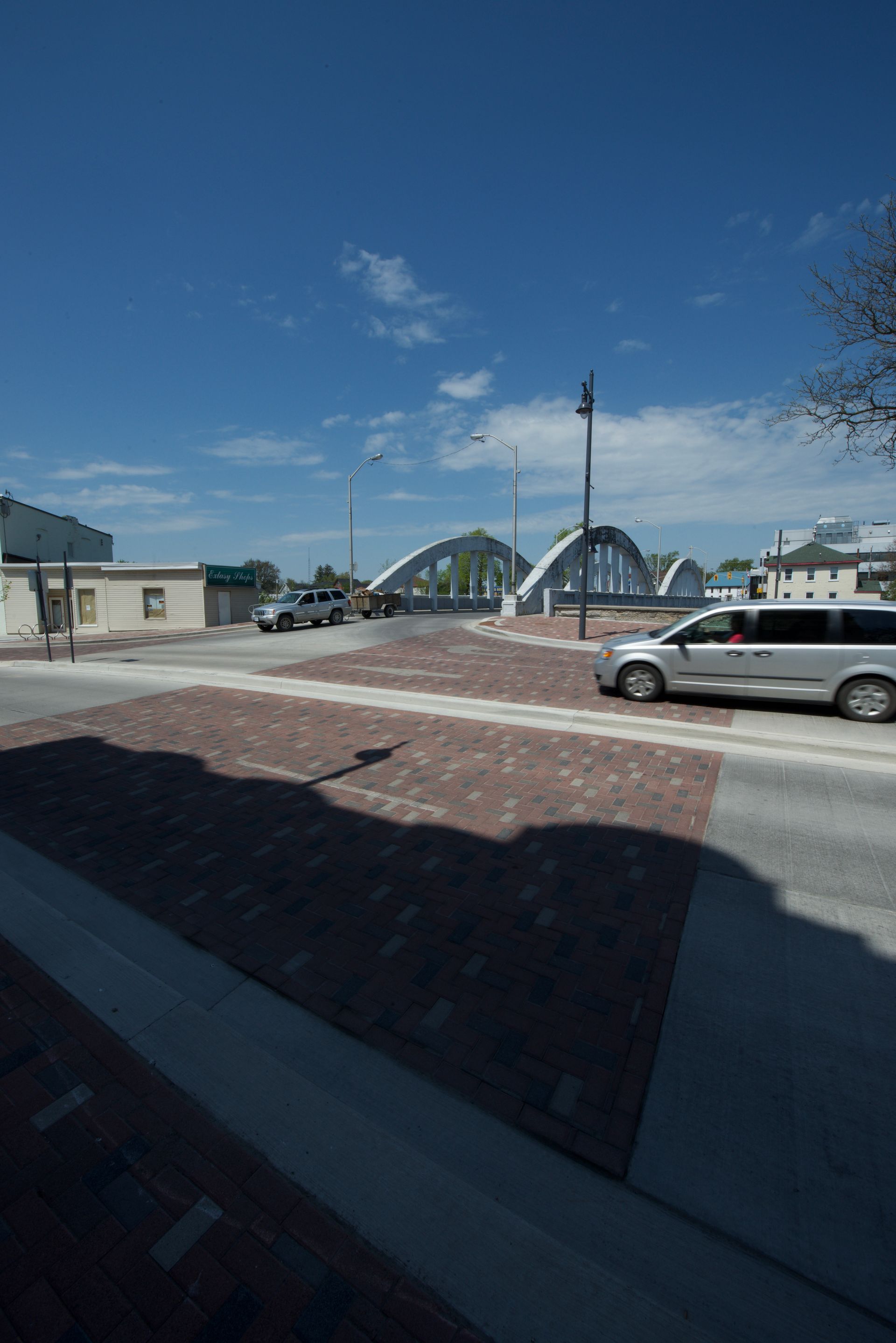 A white van is parked on the side of the road in front of a bridge.