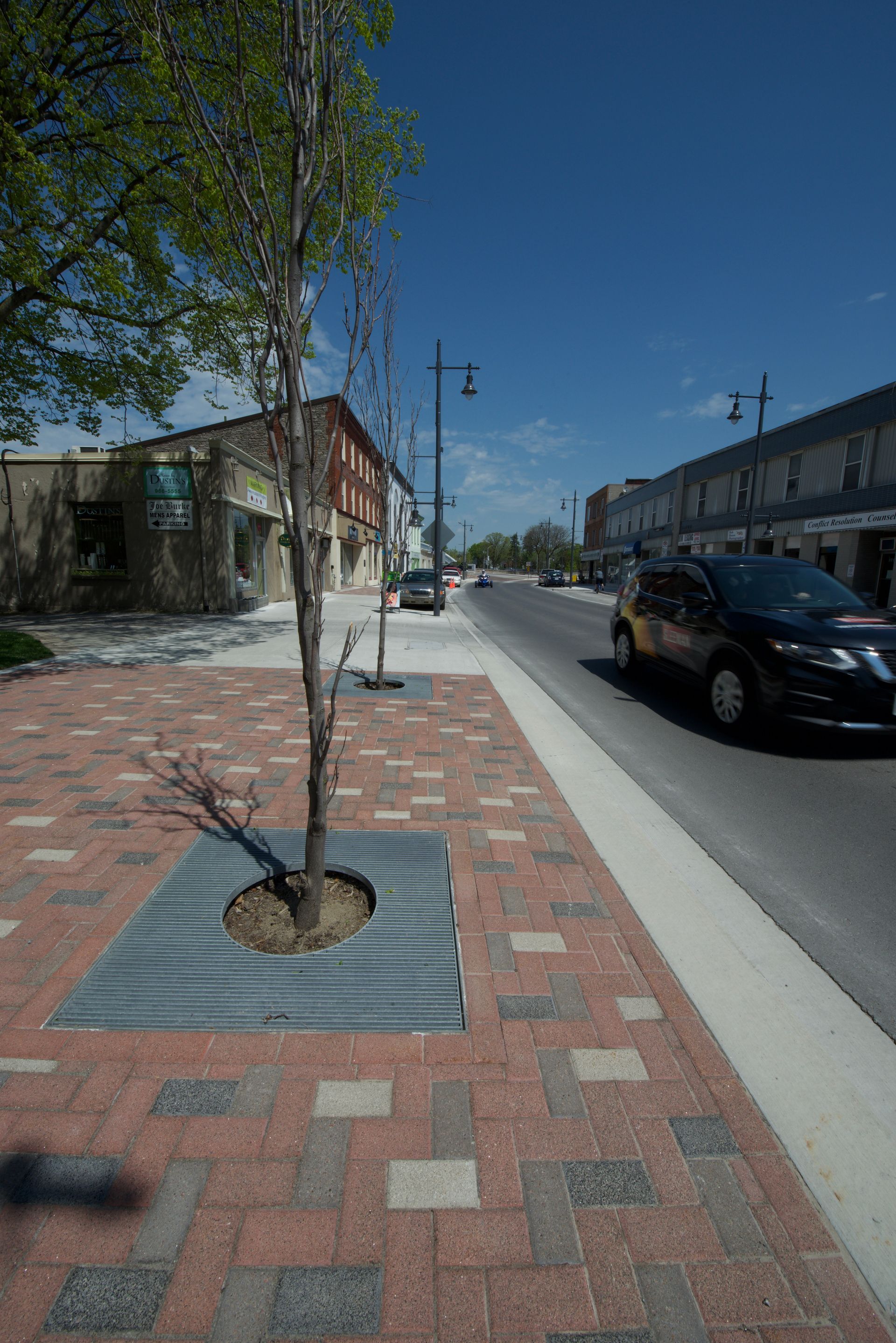 A car is parked on the side of the road next to a tree.