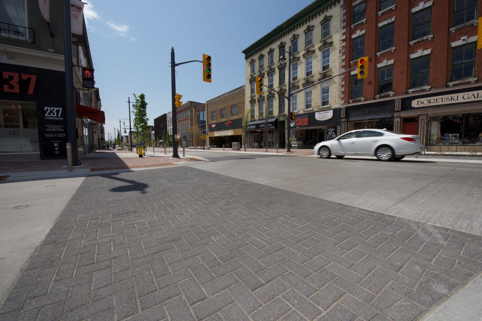 A white car is driving down a street in front of a building with the number 37 on it