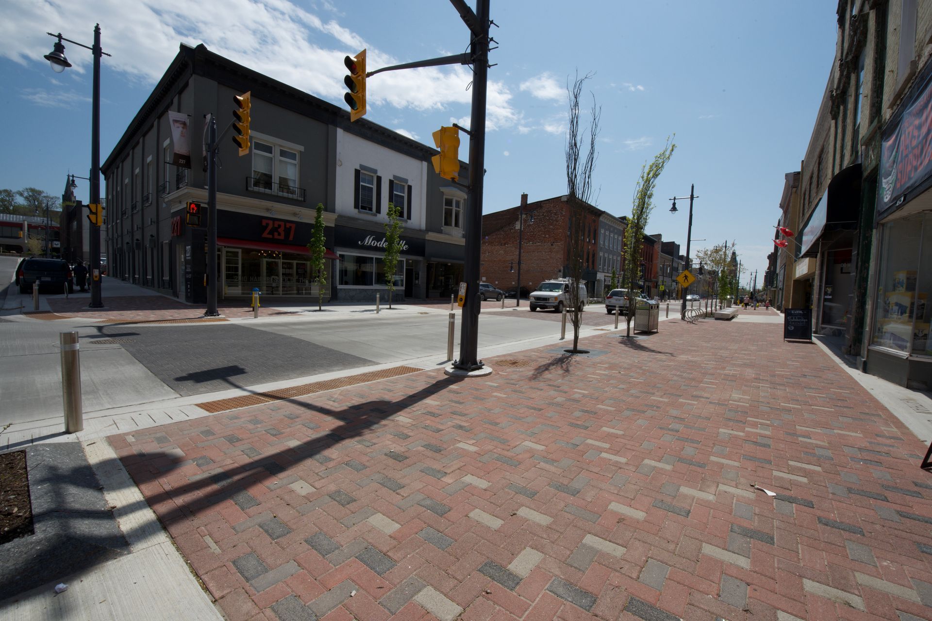 A city street with a brick sidewalk and a building in the background
