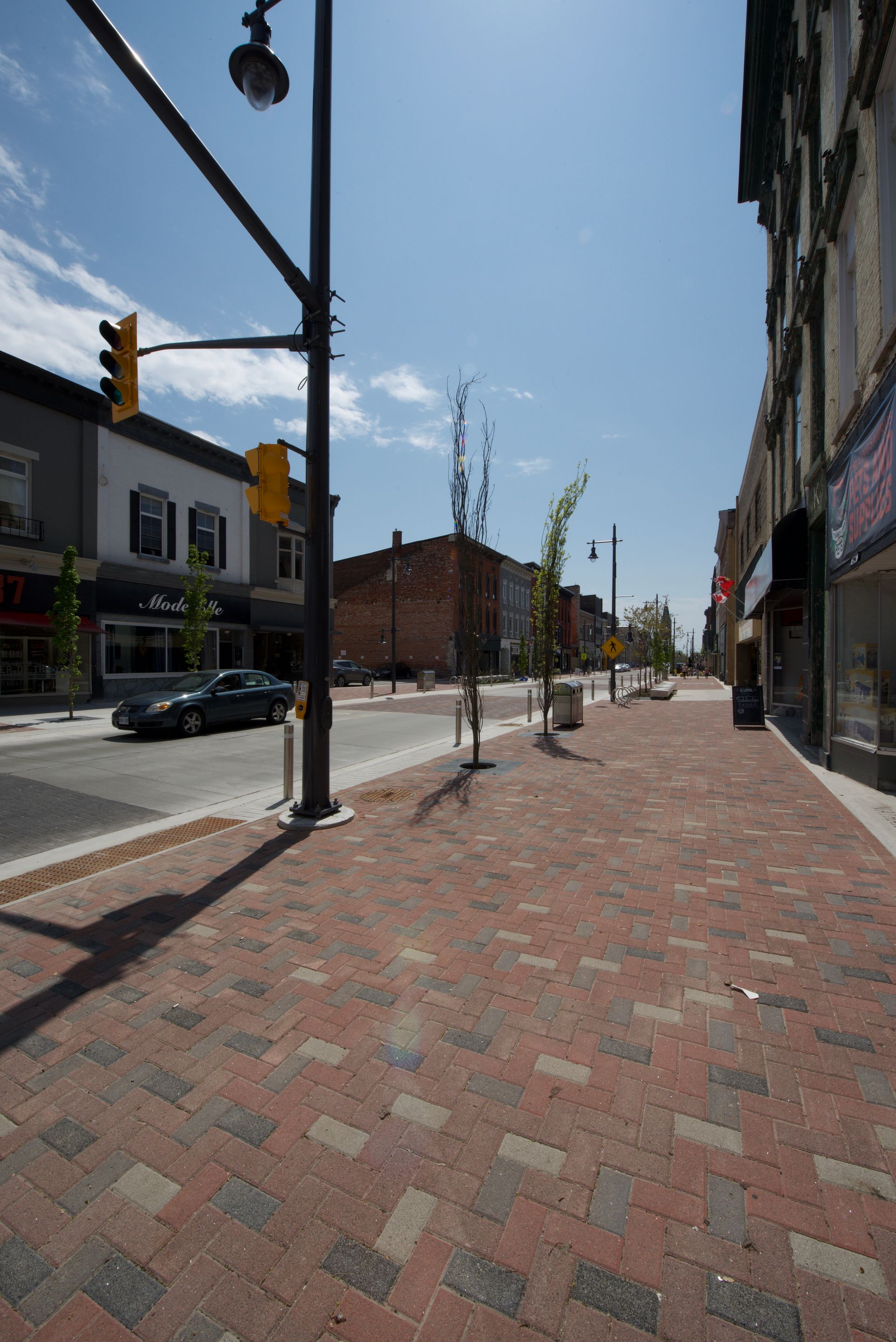 A city street with a brick sidewalk and a traffic light