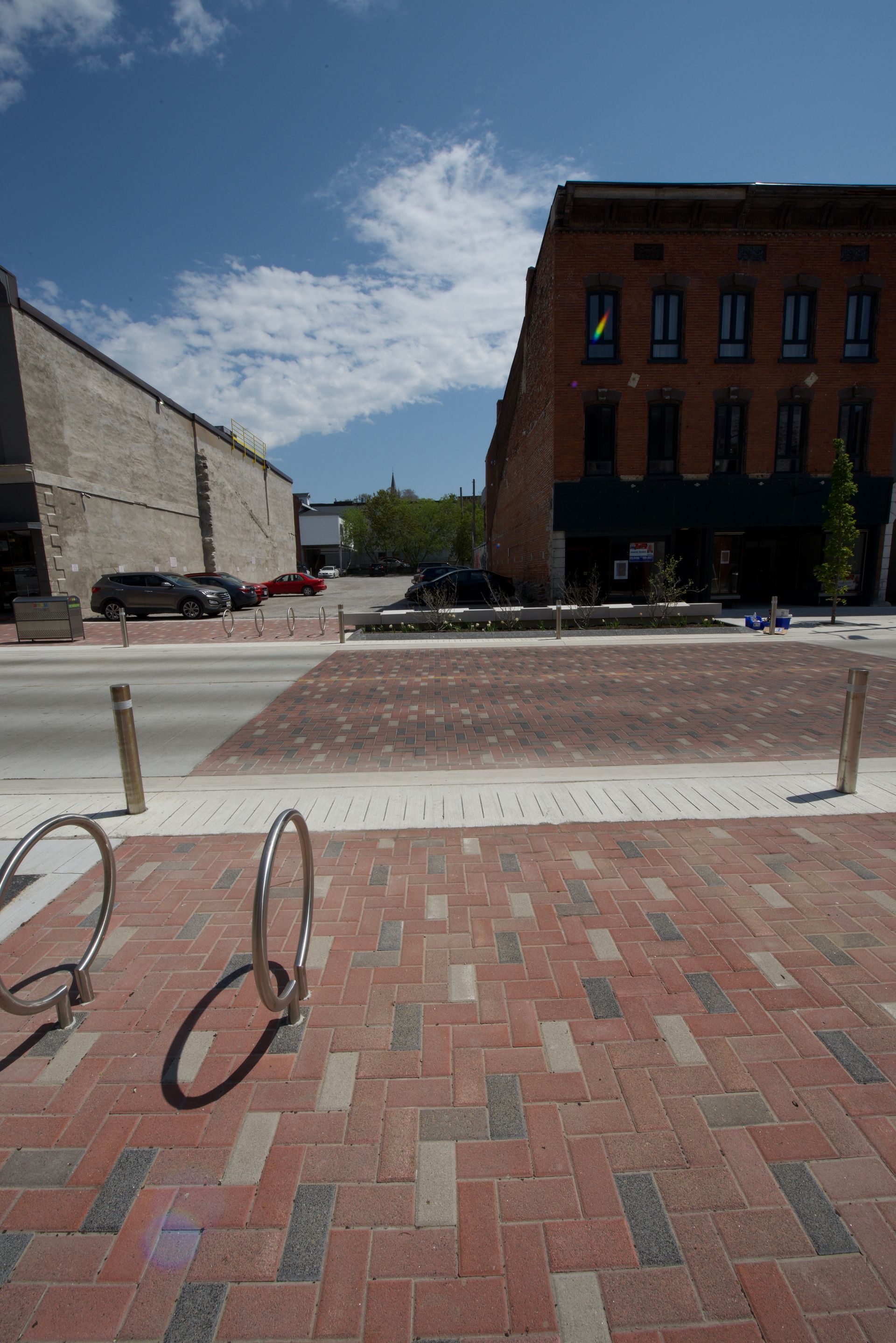 A brick sidewalk with a bike rack and a building in the background