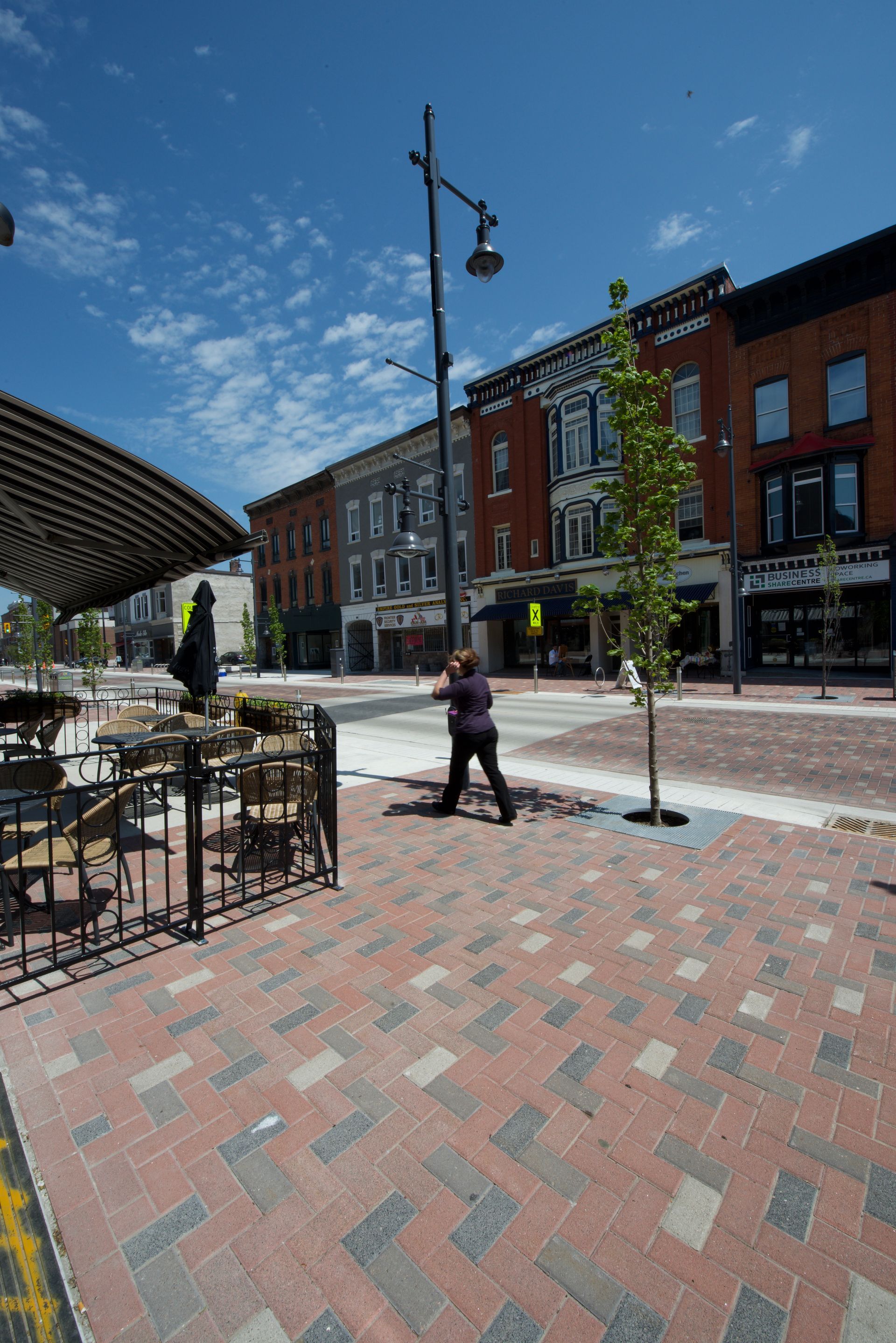 A person is walking down a brick sidewalk in a city