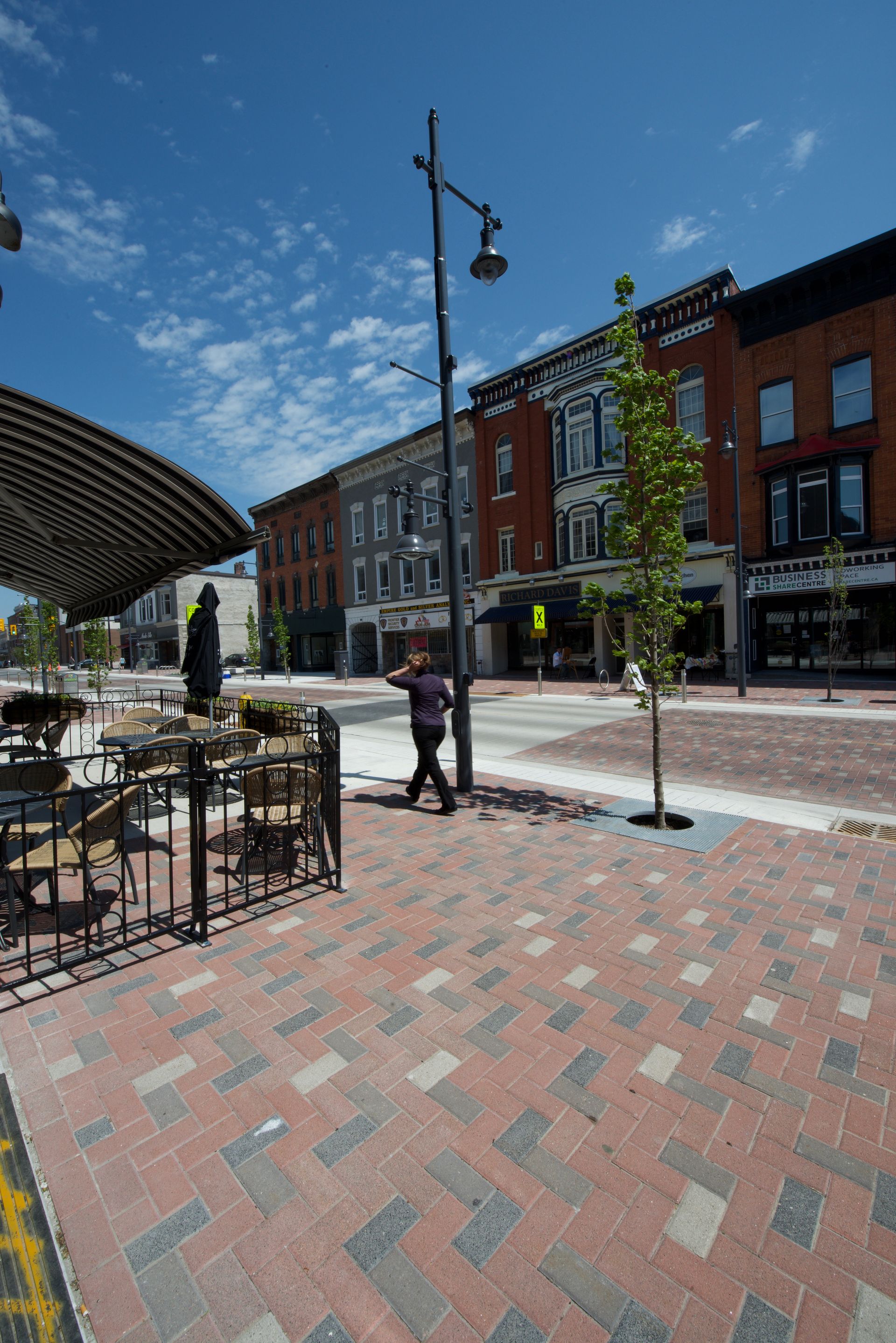 A woman is walking down a brick sidewalk in a city.