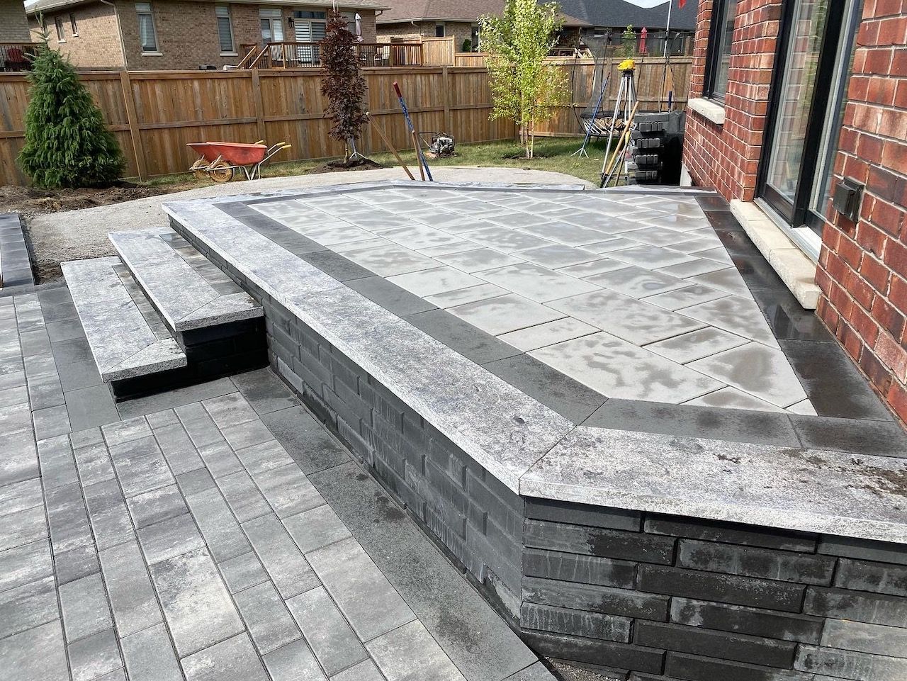 A brick patio with steps and a brick wall in front of a brick house.