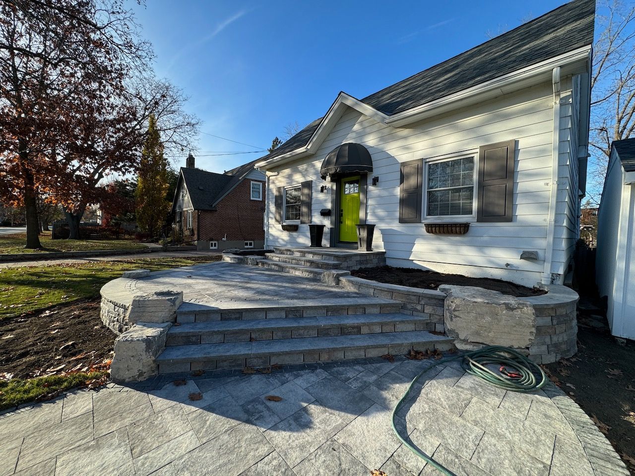 A white house with a green door and a hose in front of it.