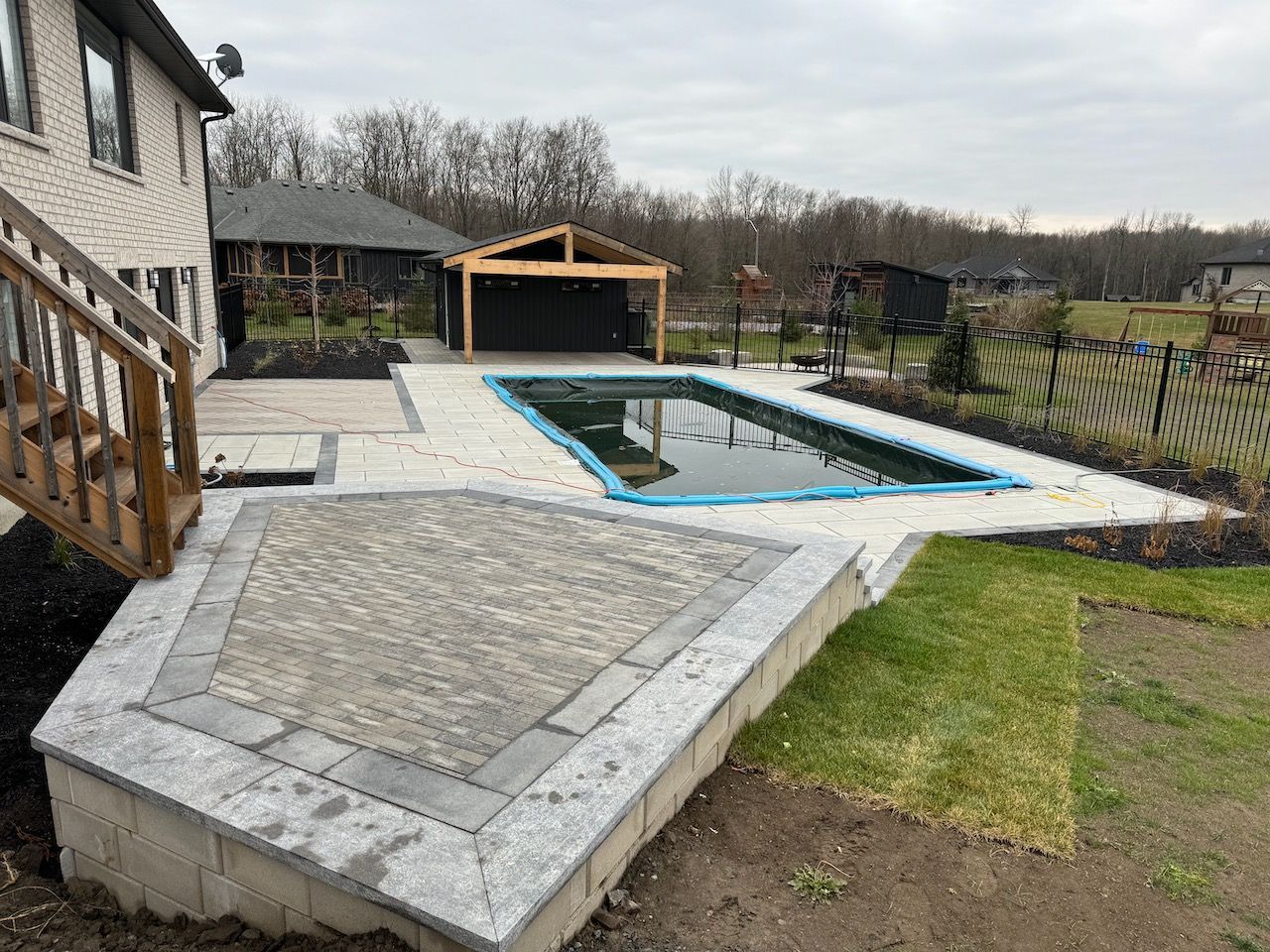 A large swimming pool is in the backyard of a house.