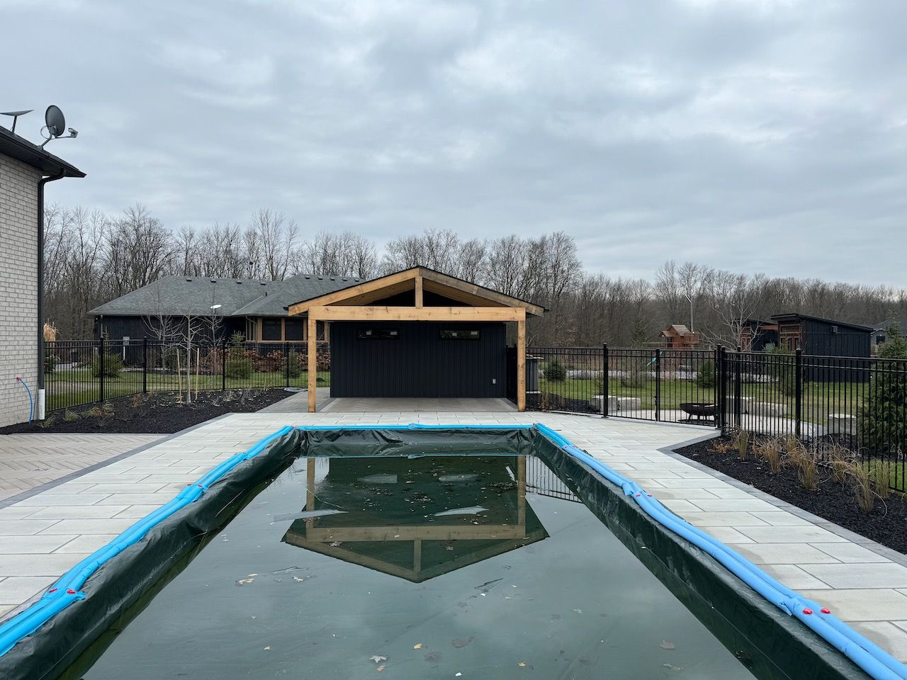 A large swimming pool in front of a house with a garage.