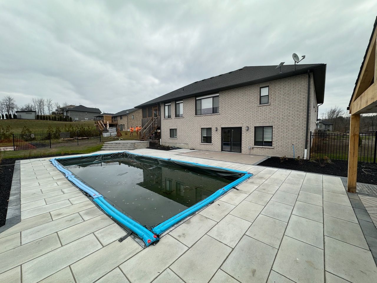 A large swimming pool is in the backyard of a house.