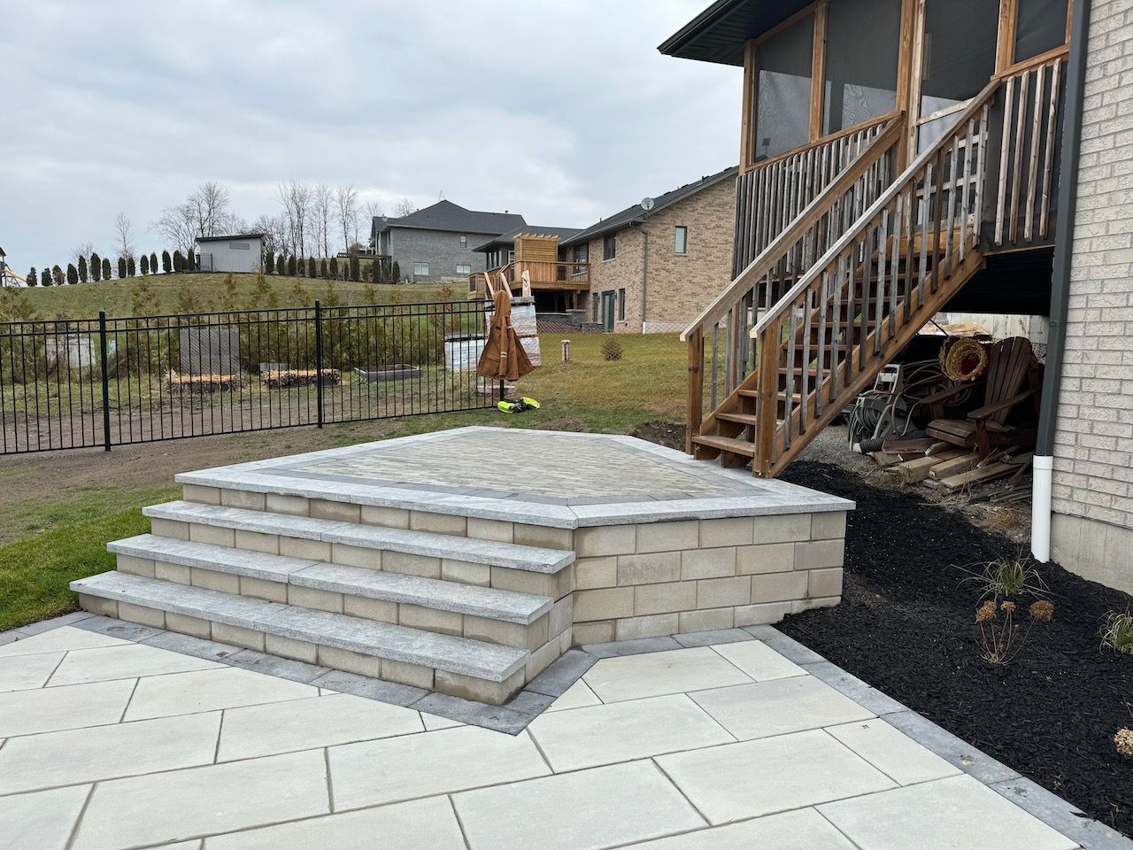 A patio with stairs leading up to a screened in porch.