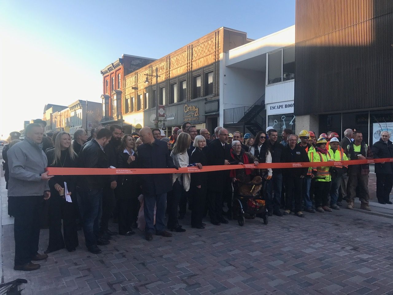 A large group of people are standing in front of a building cutting a ribbon.