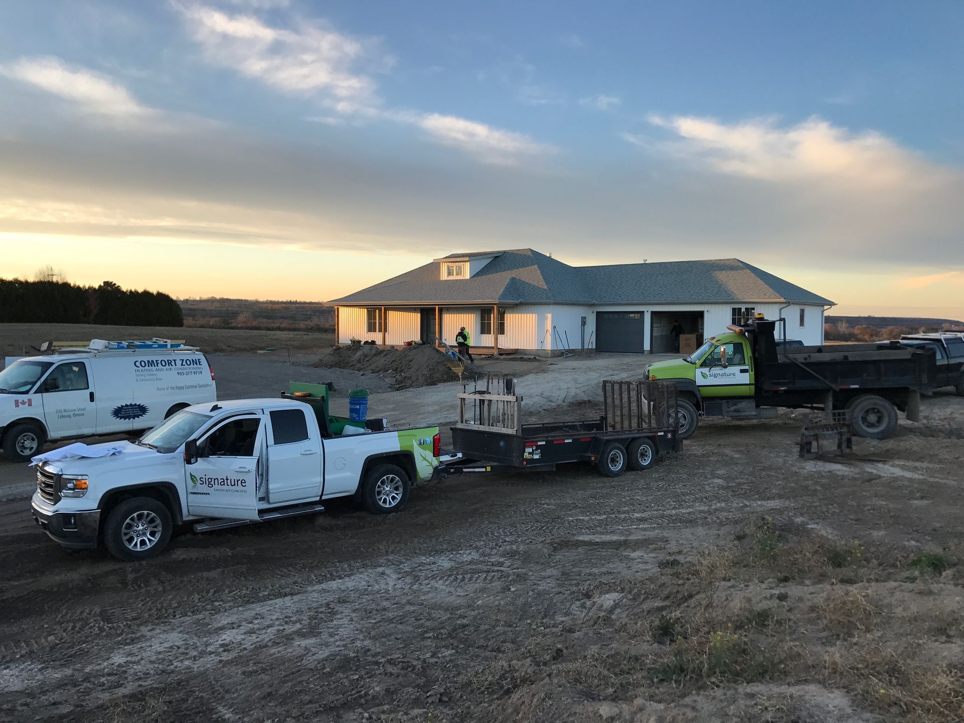 Two trucks are parked in front of a house under construction.