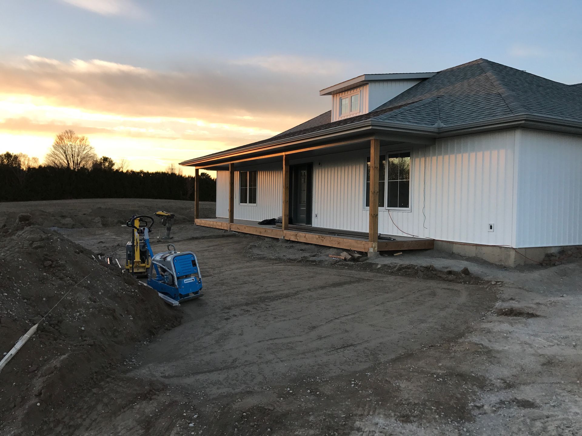 A white house is being built in a dirt field.