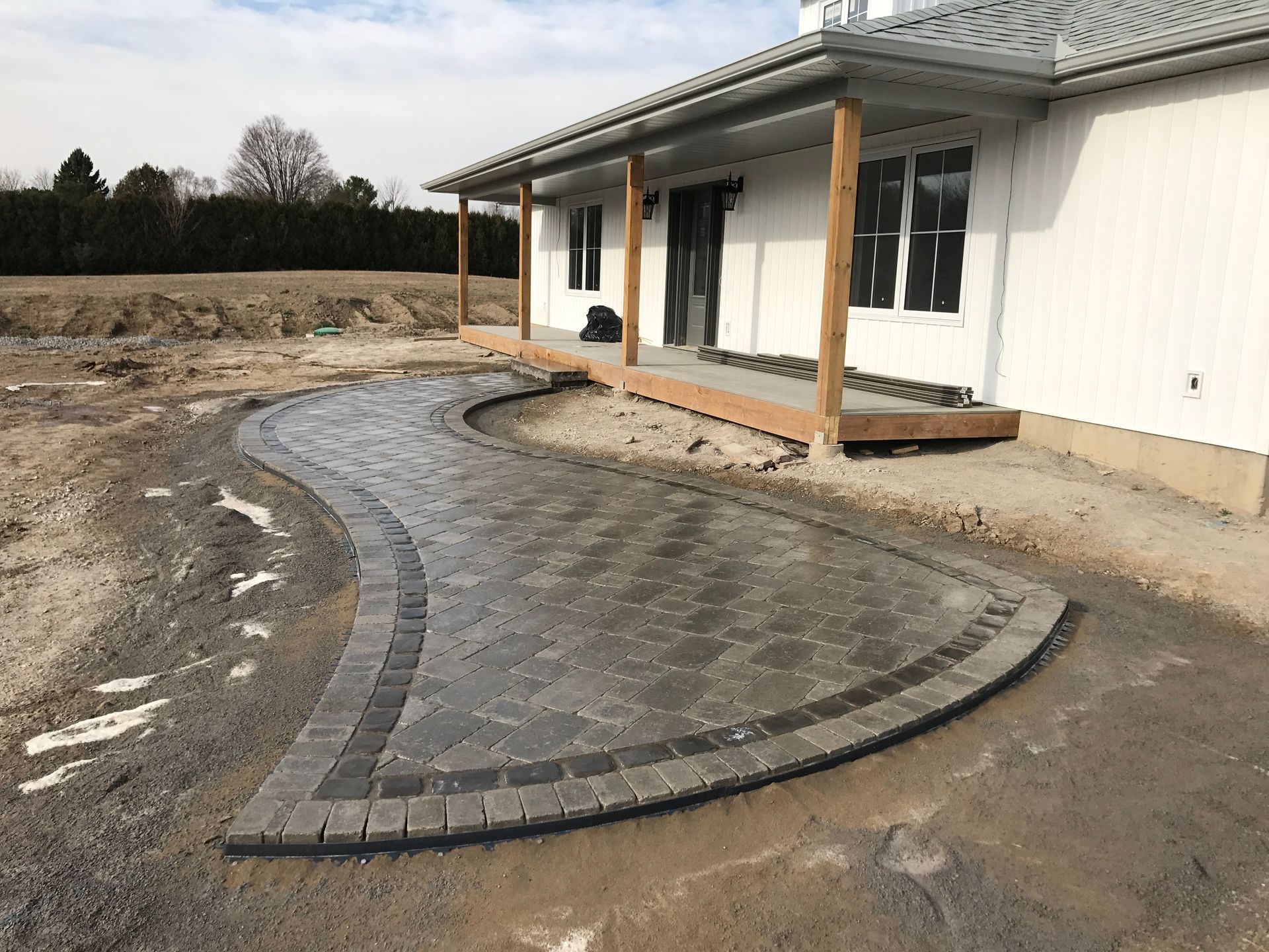 A brick walkway is being built in front of a white house.