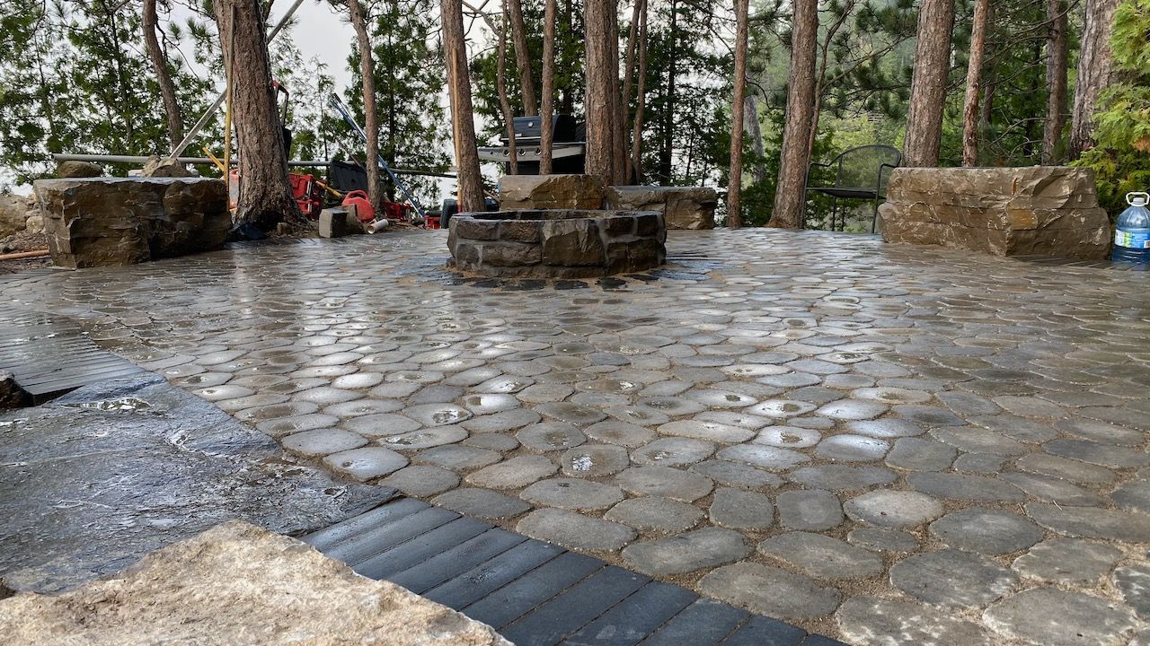 A stone patio in the middle of a forest with trees in the background.