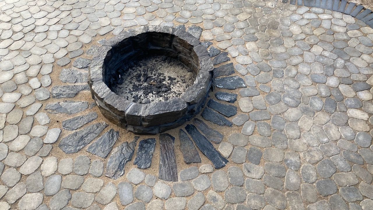 A fire pit is surrounded by bricks on a patio.