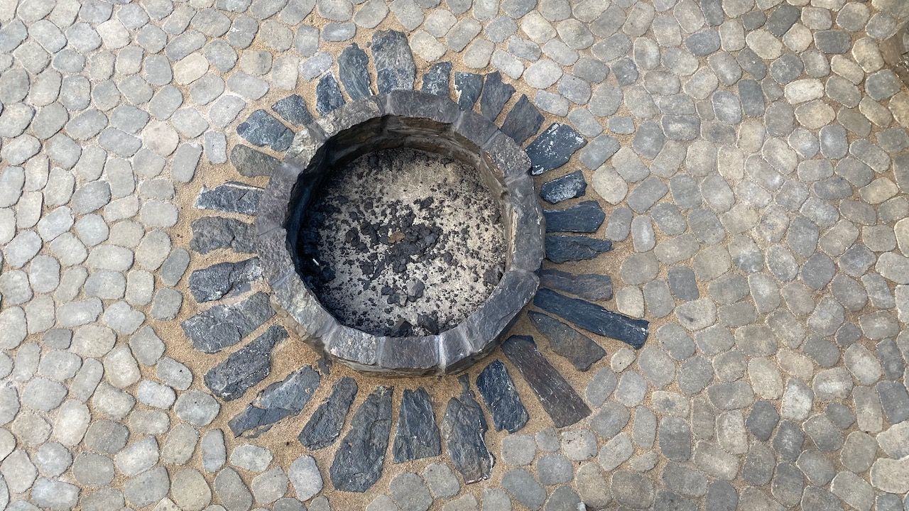 An ashtray is sitting on top of a brick floor.