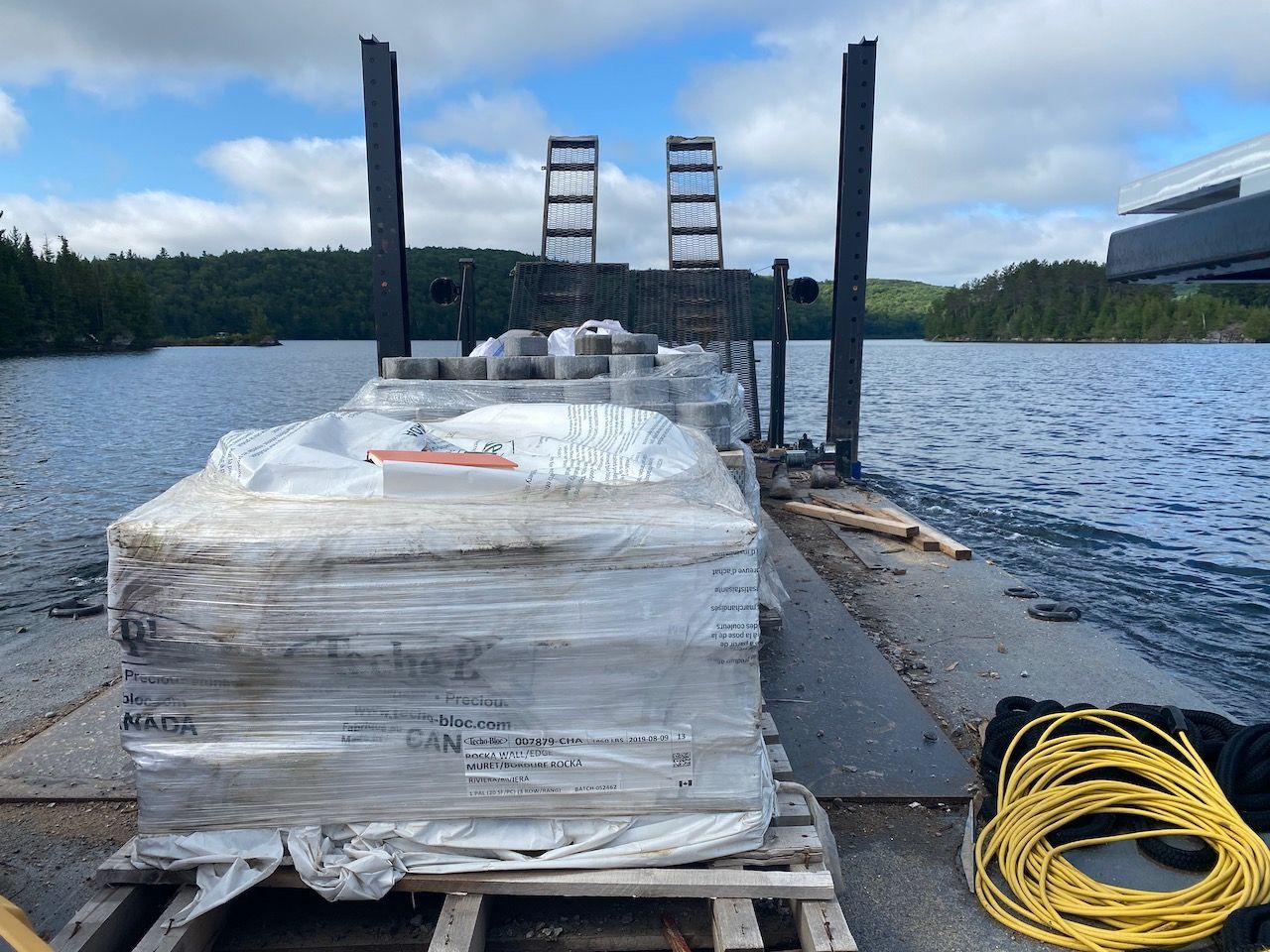 A pallet of bricks is sitting on a dock next to a body of water.