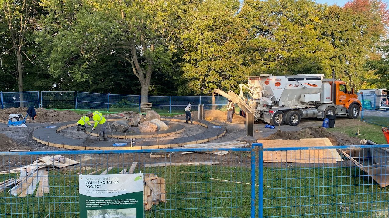 A concrete pump truck is pouring concrete into a hole in a park.