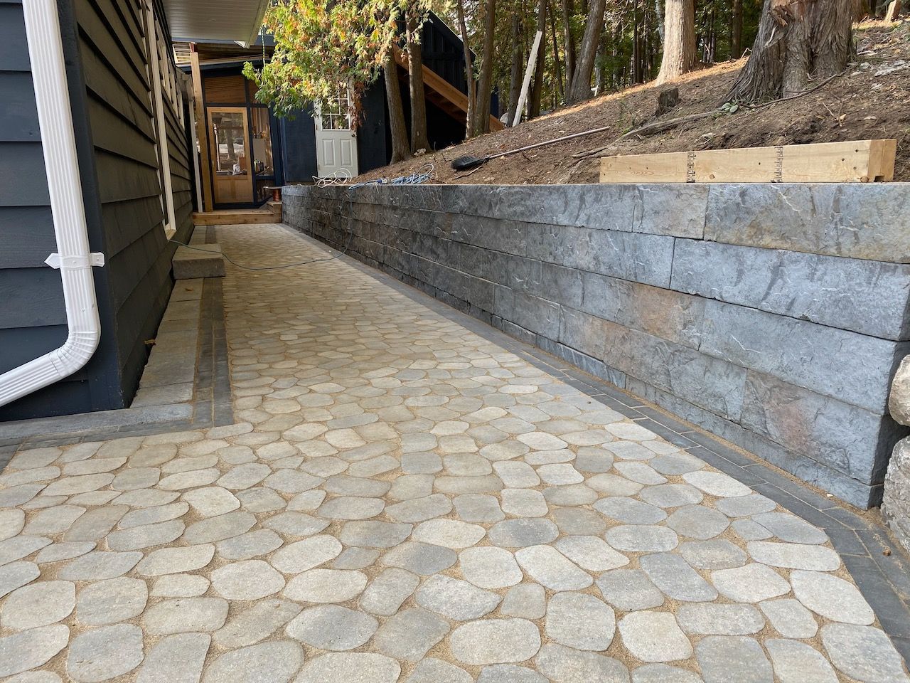 A stone walkway leading to a house with a retaining wall.