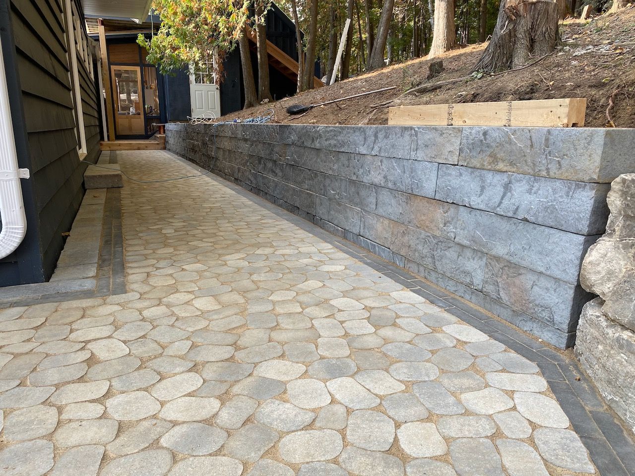 A stone walkway leading to a house with a stone wall.