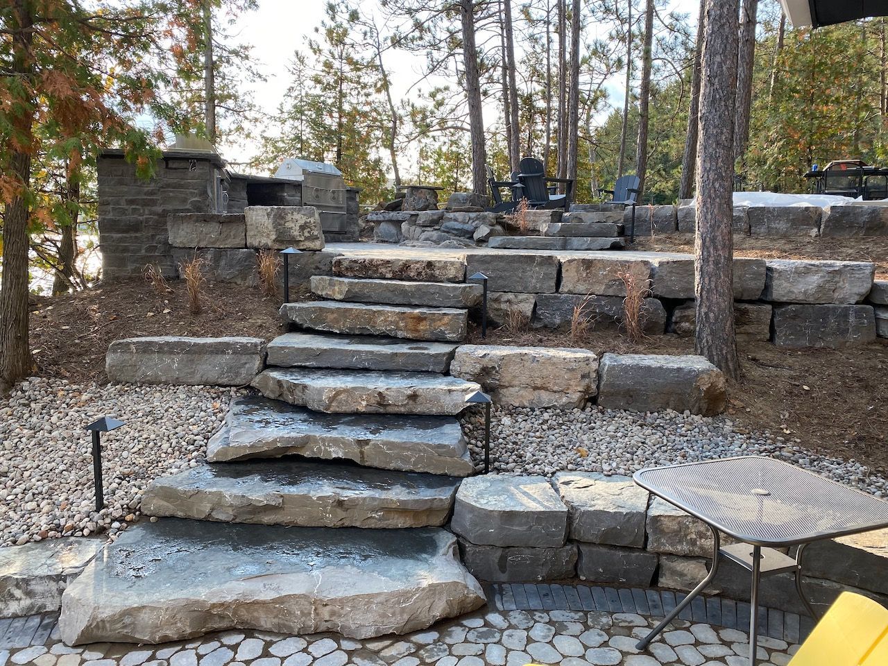 A set of stone stairs leading up to a patio in the woods